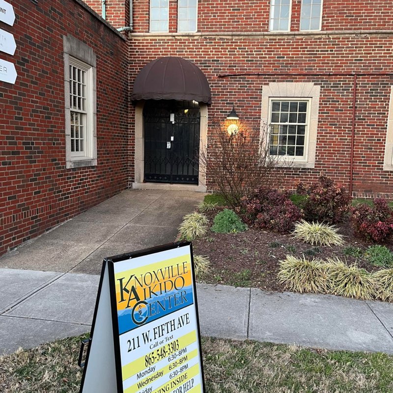 The dojo entrance at The Point: a black iron gate under a brown awning, with the Knoxville Aikido Center sign on the sidewalk